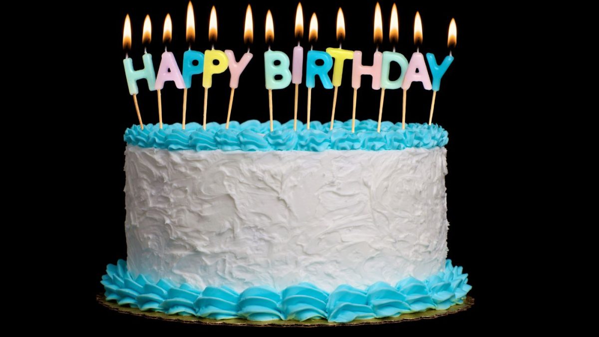 A Cake with candles spelling Happy Birthday.